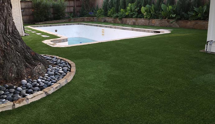 Artificial grass installed around an empty backyard swimming pool
