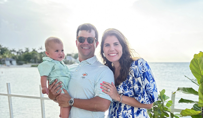 Happy family standing together on a waterfront patio overlooking a calm ocean view