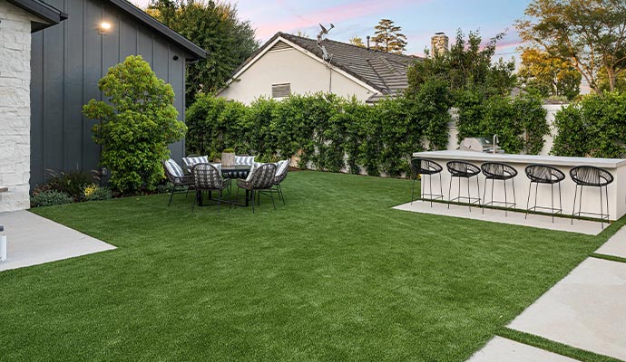 Backyard featuring an artificial grass lawn with a comfortable outdoor seating area and a stylish bar counter
