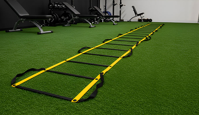 Fitness training gym featuring artificial turf flooring, agility ladder and various workout equipment