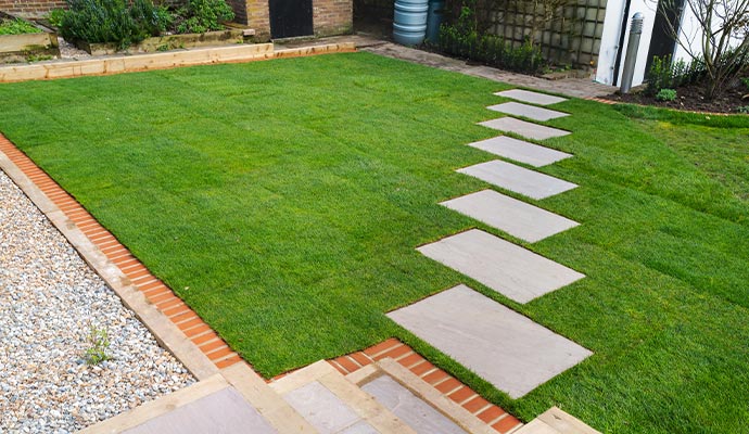 Residential backyard with newly installed landscape turf and a decorative stone pathway