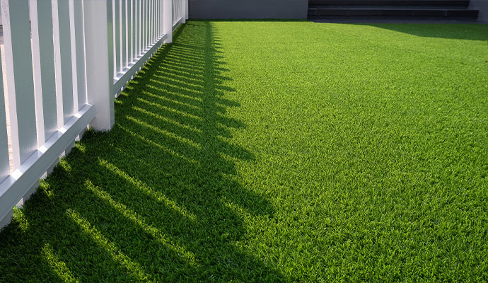 Artificial grass yard with white fence
