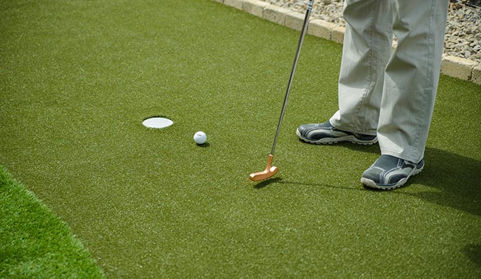 Person playing golf on an artificial putting green with synthetic turf